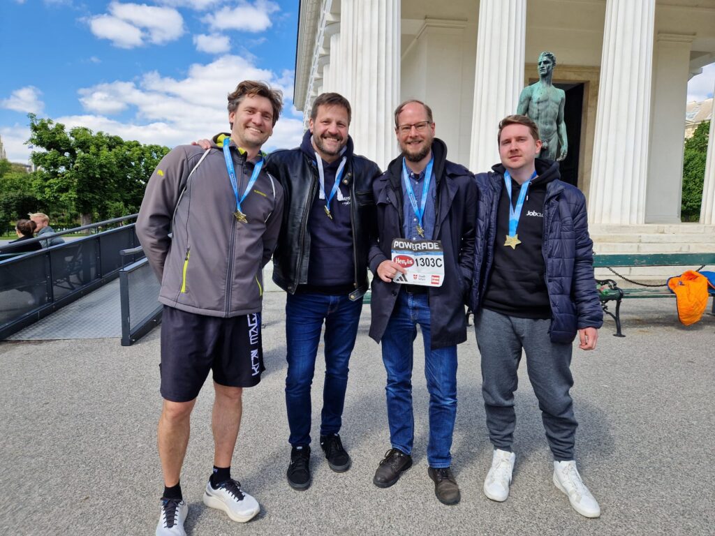 Vier Teammitglieder der JobCloud HR Tech präsentieren stolz ihre Medaillen des Vienna City Marathons.